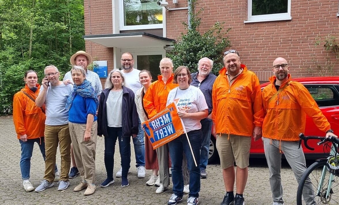 Streik beim NDR - Gruppe von Menschen steht in einer Reihe vor einem Gebäude – Im NDR-Studio in Oldenburg wurde im August erneut gestreikt. Vorne mit Plakat: DJV-Landesgeschäftsführerin Christiane Eickmann