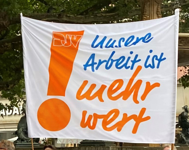 Protestplakat mit Aufschrift "Unsere Arbeit ist mehr wert!" – 